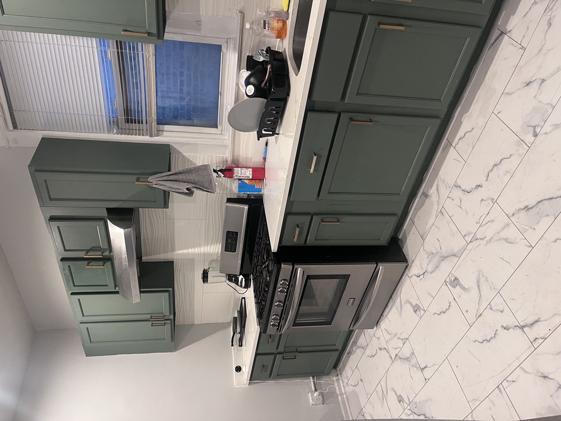 Kitchen with green cabinets, a gas range, and a window over the sink