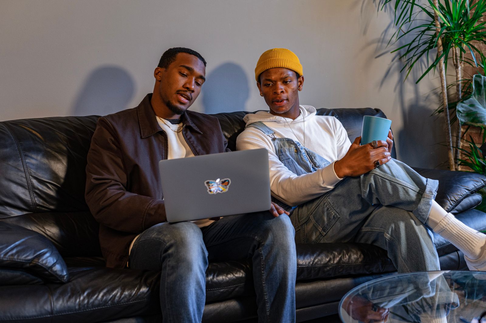 Two people sitting on a couch looking at a laptop