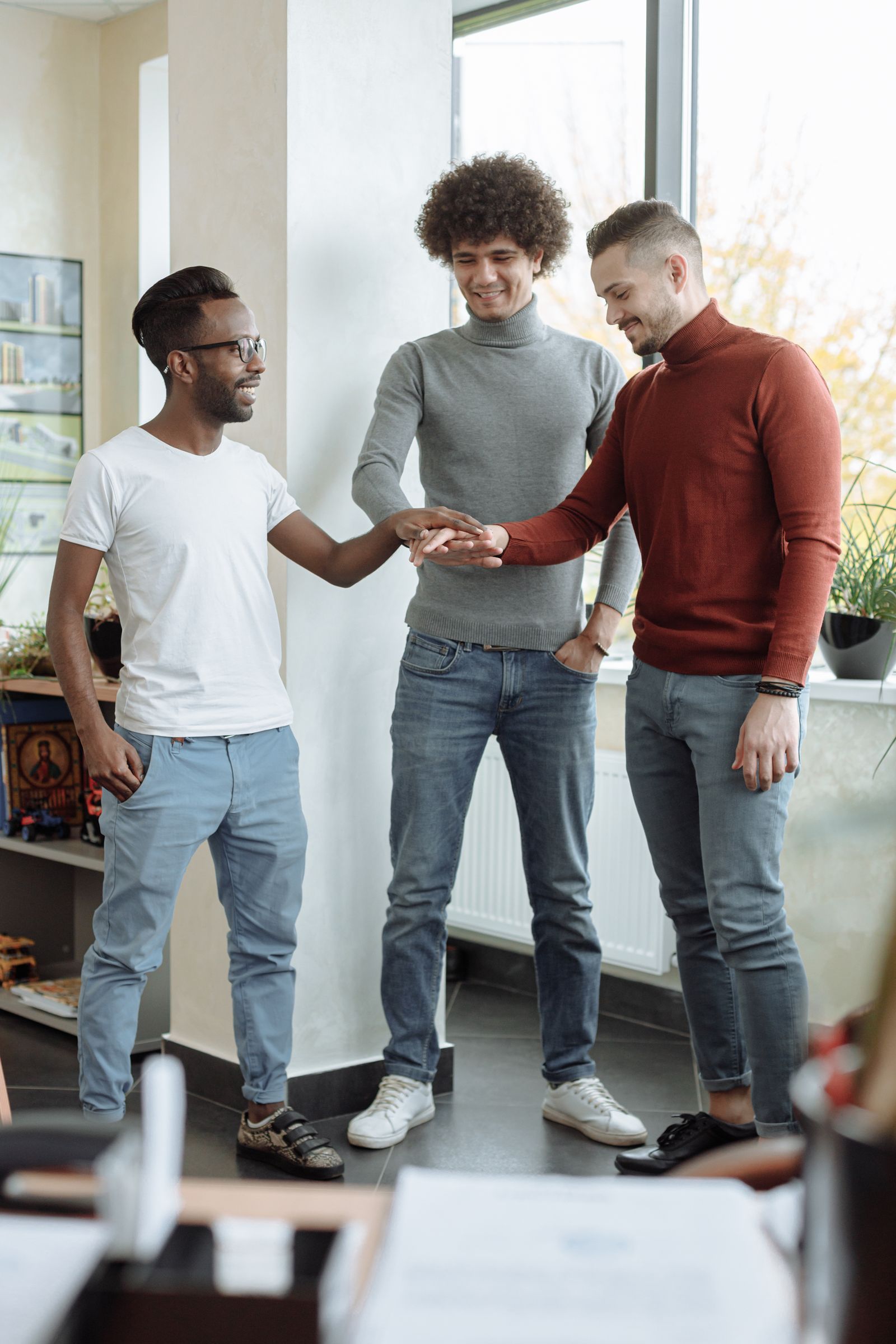 Three people standing together and stacking their hands